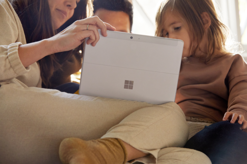 Eine Familie sitzt auf der Couch mit ihrem Surface Go 2