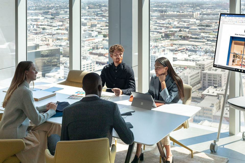 Vier Personen sitzen an einem Tisch im Konferenzraum und unterhalten sich