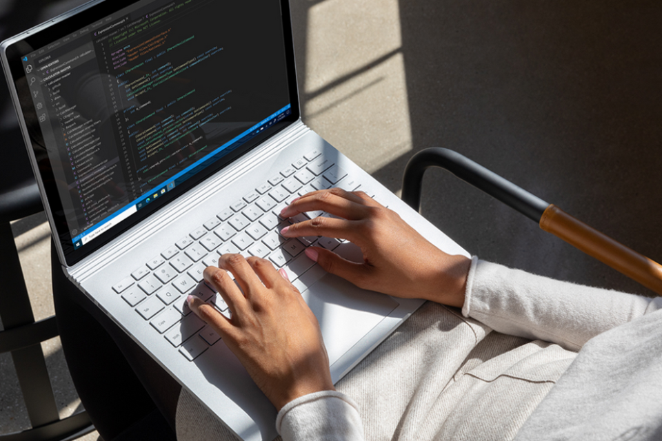 Person tippt auf der Tastatur eines Surface das auf ihrem Schoß steht
