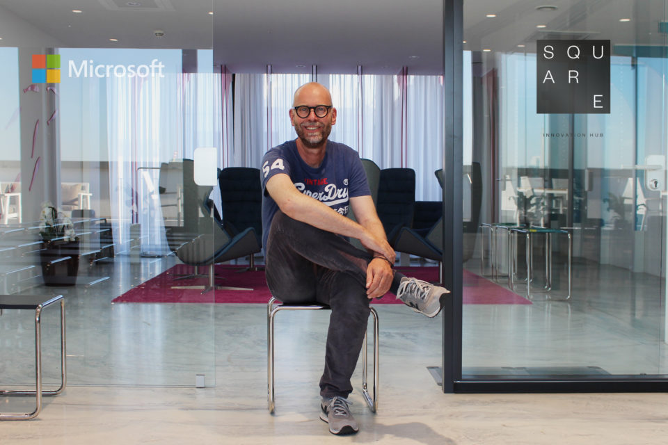 Dr. Uve Samuels, Geschäftsführer SQUARE Innovation Hub, im SQUARE-Standort im „Hamburger Ding“. Links ein Microsoft- und rechts ein SQUARE-Logo.
