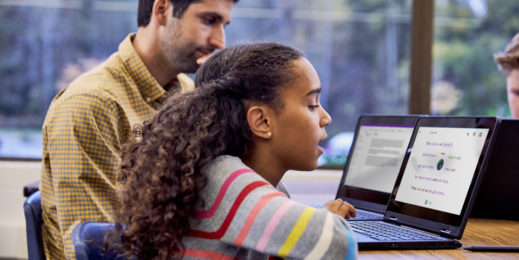 Schülerin lernt mit Hilfe eines Laptops und des Immersive Reader lesen, während ihr Lehrer daneben sitzt