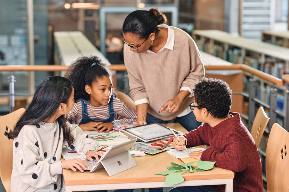 Schüler:innen lernen in Begleitung einer Lehrerin mit Surface Geräten