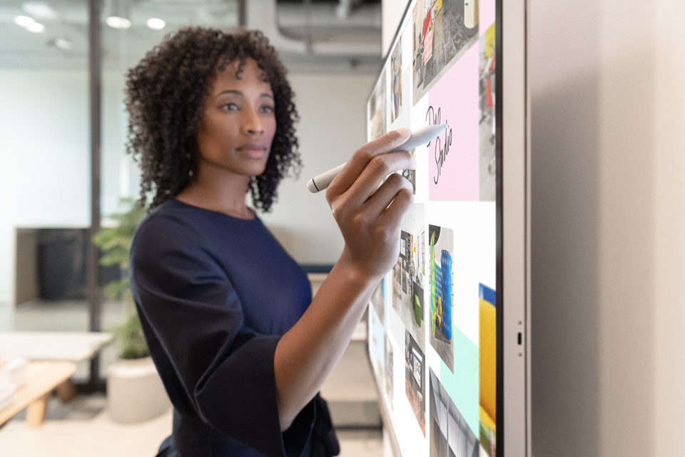 Eine weibliche Führungskraft arbeitet am Surface Hub 2S in Whiteboard mit Surface Hub 2 Stift.
