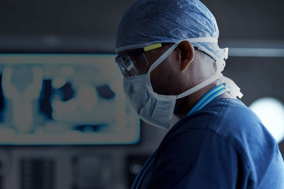 Microsoft Cloud for Healthcare_ Arzt steht im OP mit Mund-und Nasenschutz
