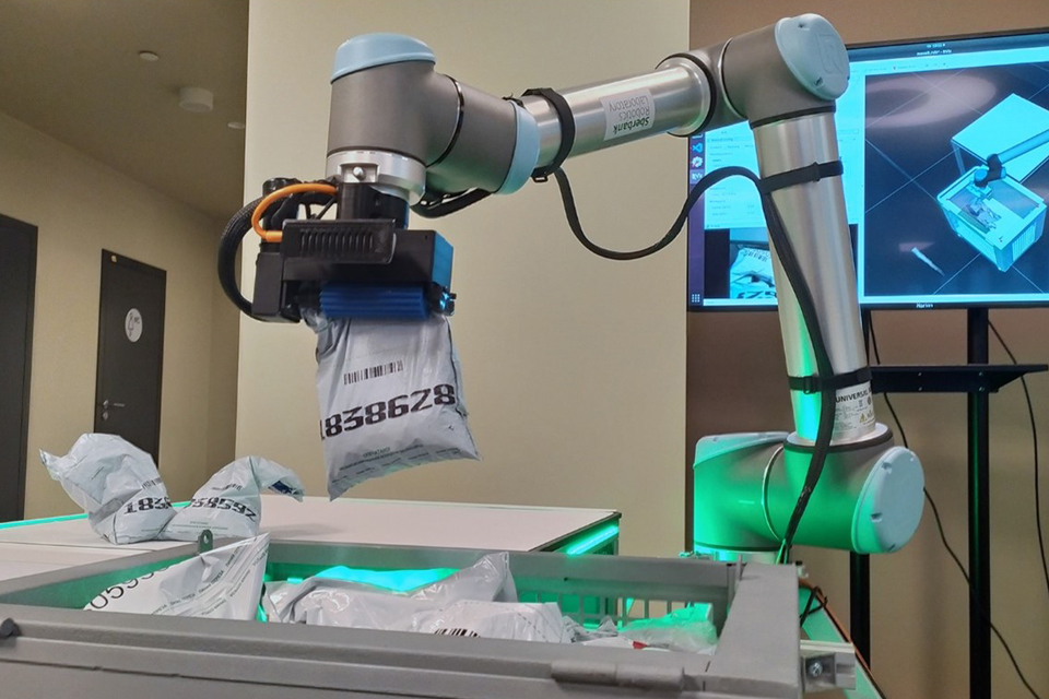 Ein Roboterarm greift nach weißen Beuteln. Die Beutel sind nummeriert