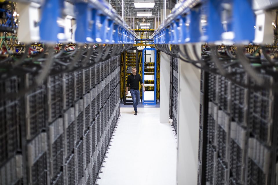 Mensch läuft durch einen Raum voller Server
