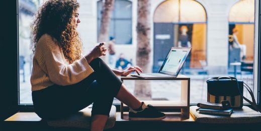 Auf der Fensterbank eine Frau mit Computer