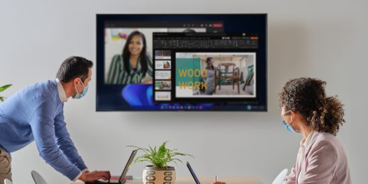 Ein Mann und eine Frau sitzen vor einem Laptop und gucken auf einen Screen