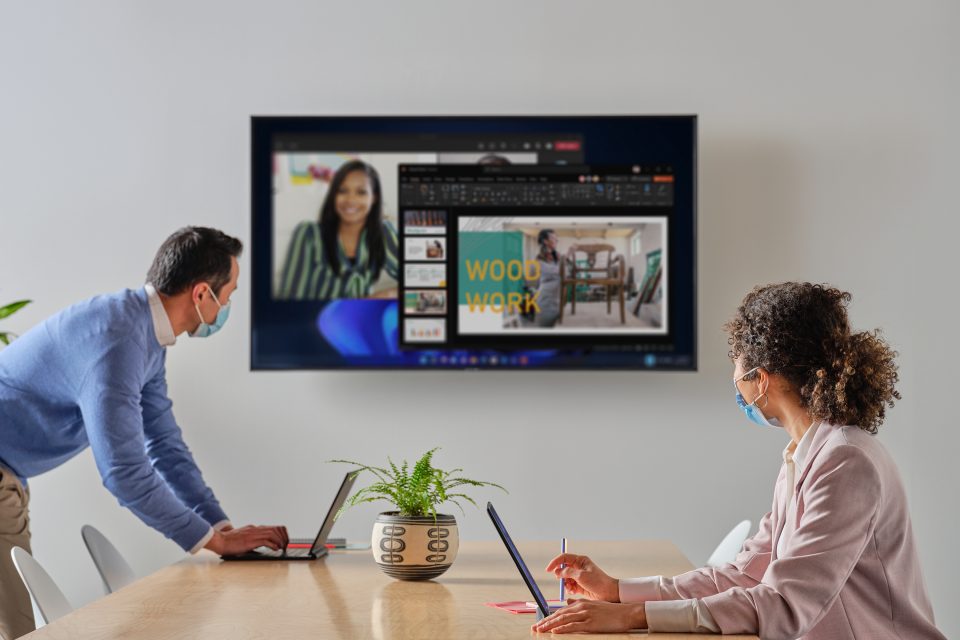 Ein Mann und eine Frau sitzen vor einem Laptop und gucken auf einen Screen