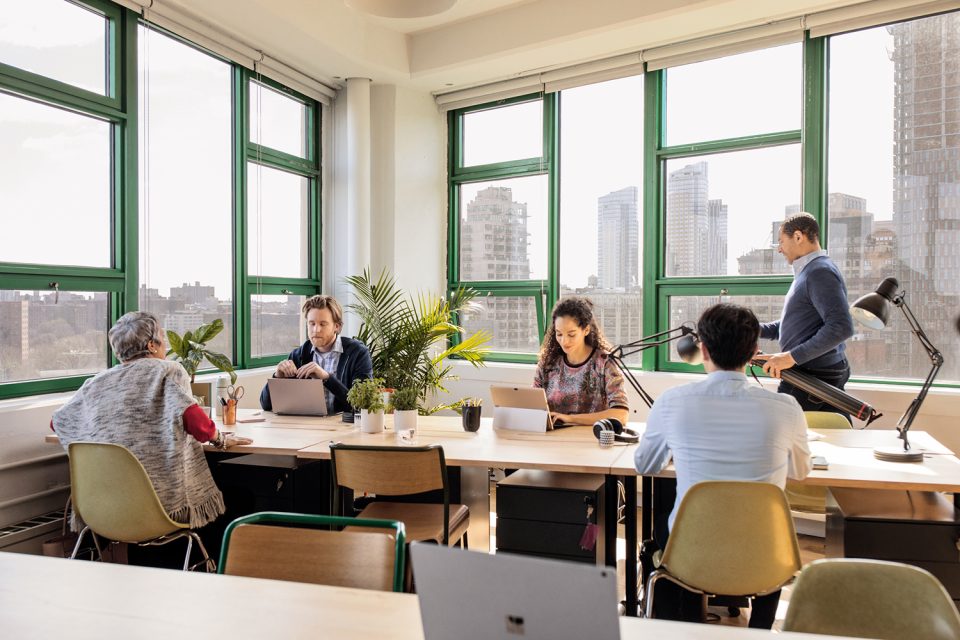 Menschen sitzen gemeinsam an einem großen Tisch und arbeiten.
