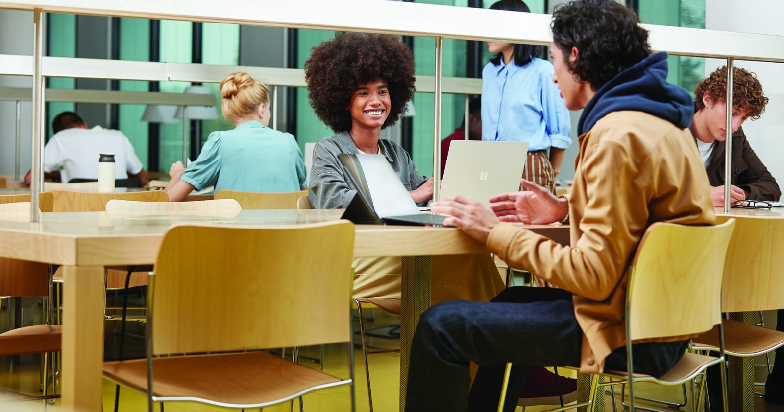 Eine Frau und ein Mann sitzen gemeinsm am Tisch vor Laptops