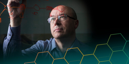 Christopher Bishop zeichnet an eine transparente Wand umgeben von Molekülen.