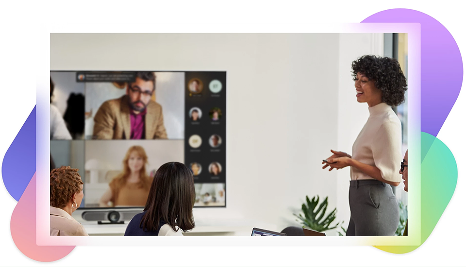 Besprechungssituation mit zwei pysich anwesenden Frauen und weiteren über Teams über einen Monitor zugeschaltet