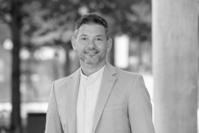 Profilbild von Reinhard Nissl, grinsend im Anzug