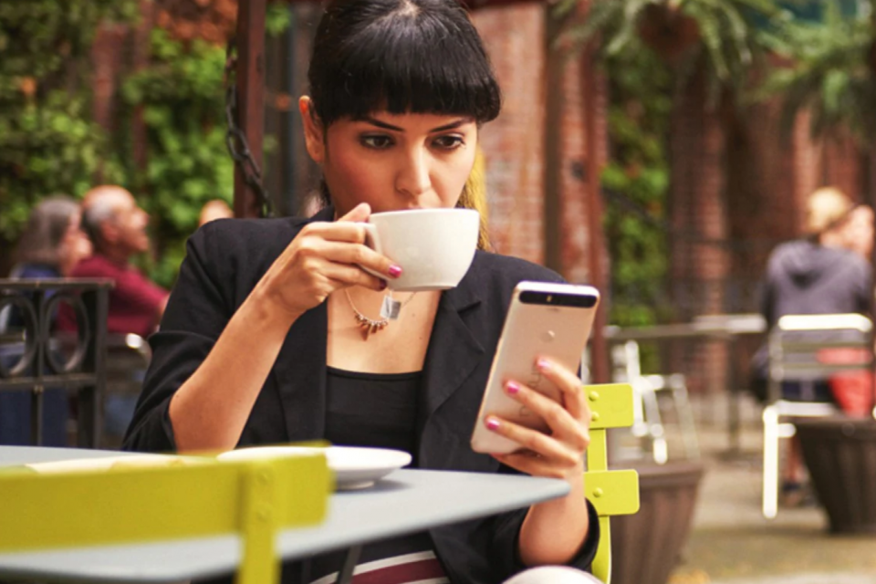 Mujer en una cafetería observa su teléfono