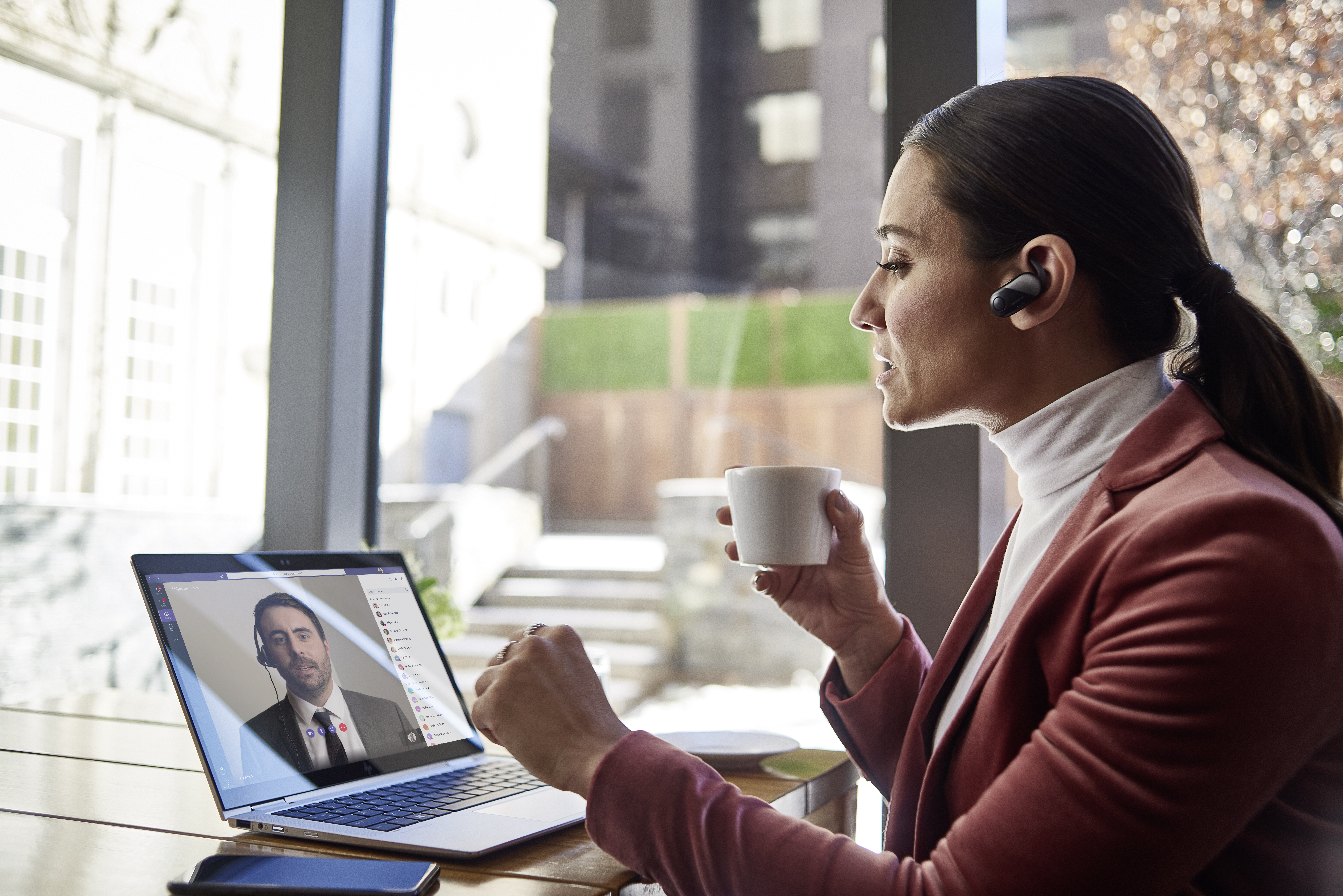 Una mujer bebe café mientras observa la pantalla de una laptop
