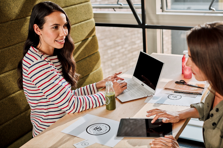 Dos mujeres en un escritorio trabajan con una laptop y una tablet