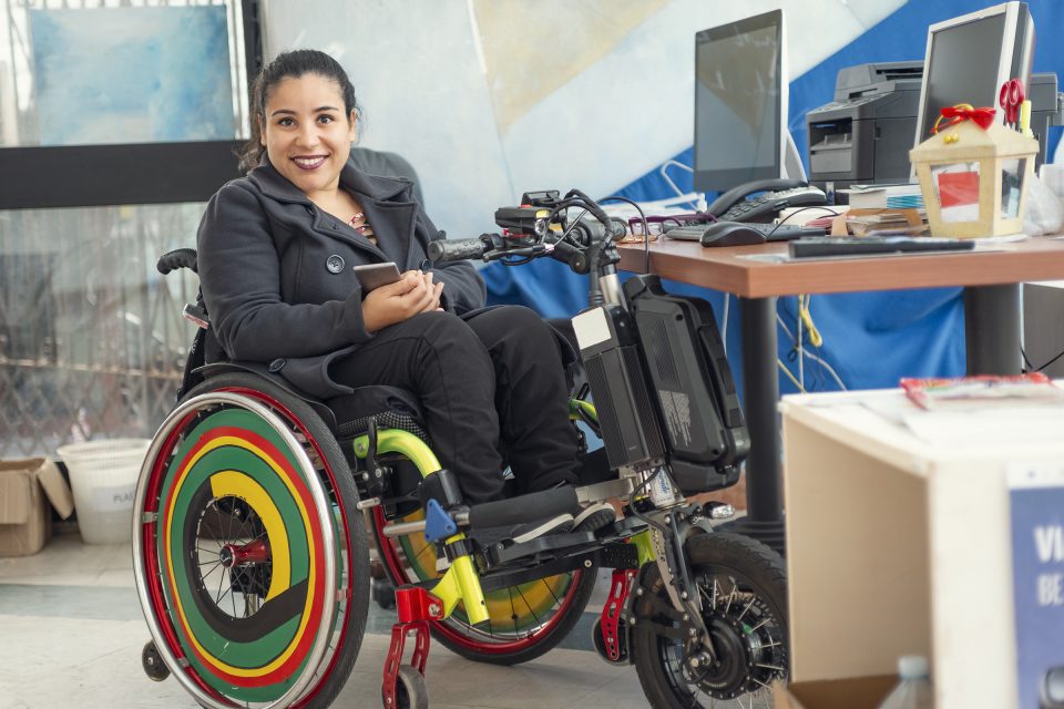 Mujer en silla de ruedas colorida en el escritorio de la computadora