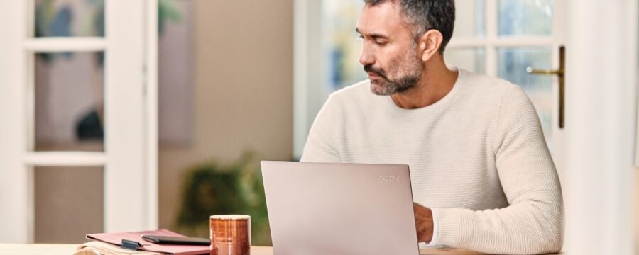 Profesional móvil mira su teléfono mientras trabaja desde casa en una computadora portátil Lenovo Yoga C930.