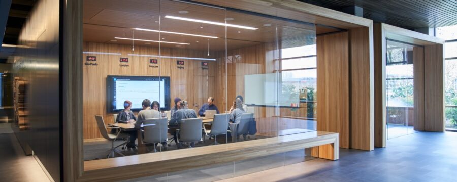 Exterior de una sala de conferencias o reunión de la mesa directiva, incluidas algunas personas sentadas alrededor de una mesa en una sala con relojes de tiempo internacional.