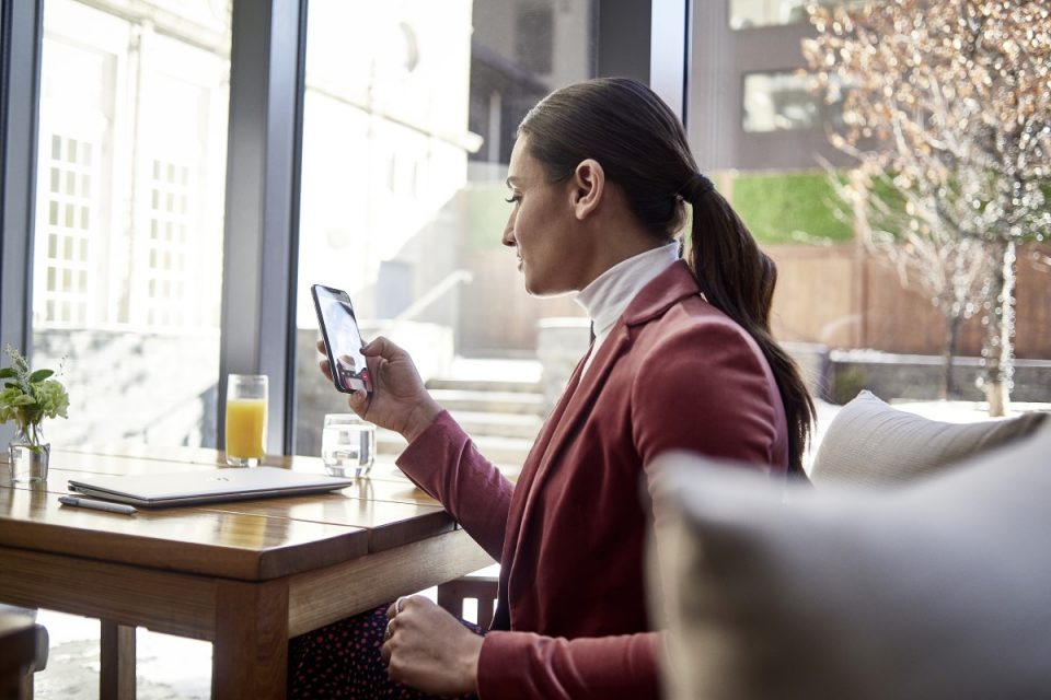 Una mujer sentada en un escritorio sostiene un smartphone