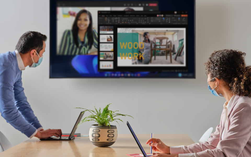 Dos personas en una sala de juntas miran una pantalla