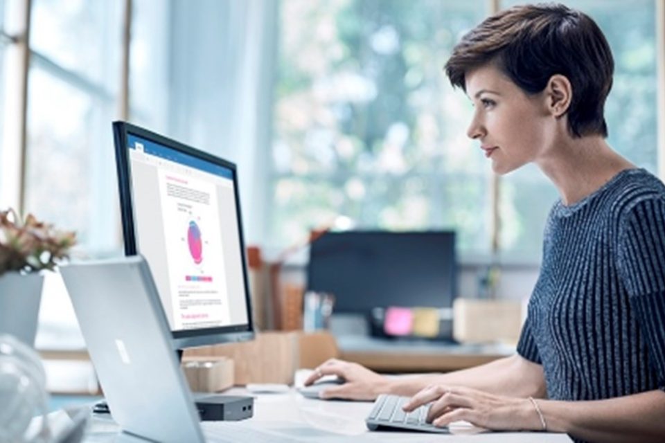 Mujer trabaja con una laptop y un monitor externo