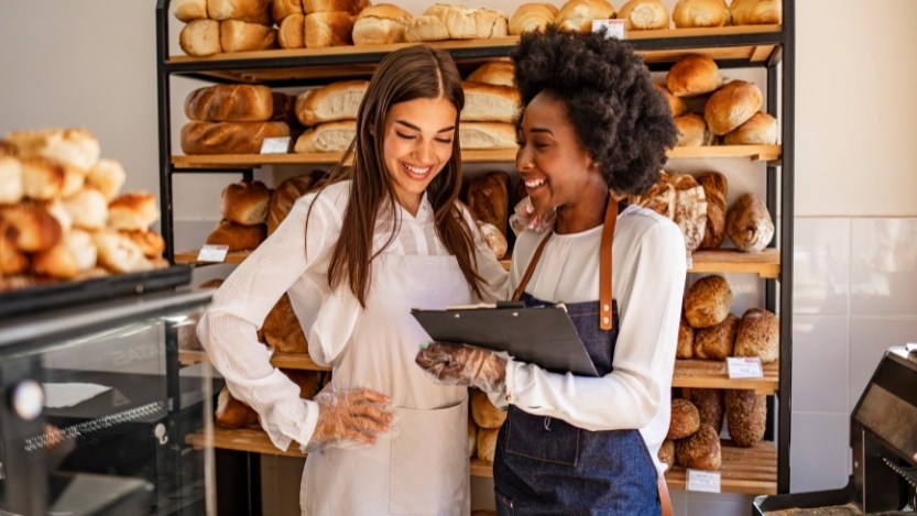 Dos mujeres que trabajan en una panadería sonríen lejos de la cámara