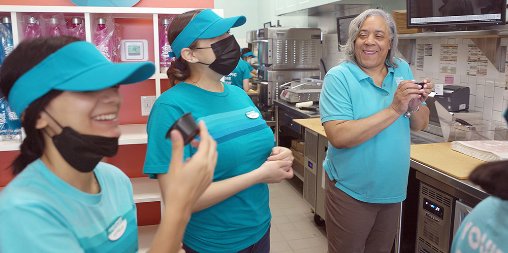 Tres personas se paran en una cocina.