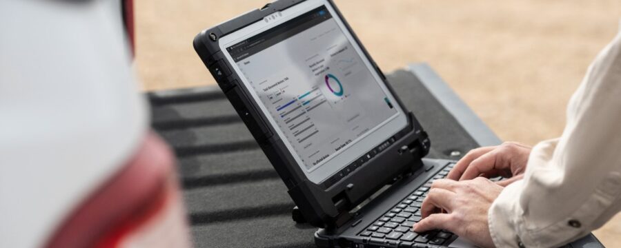 Ingeniero de campo usa una computadora portátil en el portón trasero de un camión para revisar los datos después de la inspección de las turbinas en un parque eólico.