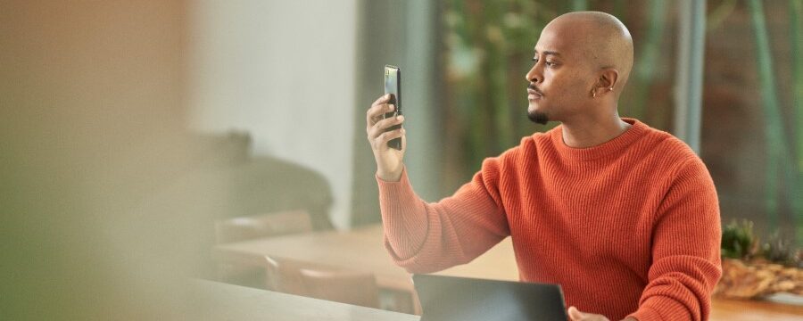 Vendedor que completa la autenticación multifactor a través del reconocimiento facial en un teléfono móvil desde Microsoft Entra antes de trabajar desde casa.