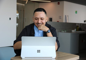 Hombre sonríe frente a una laptop