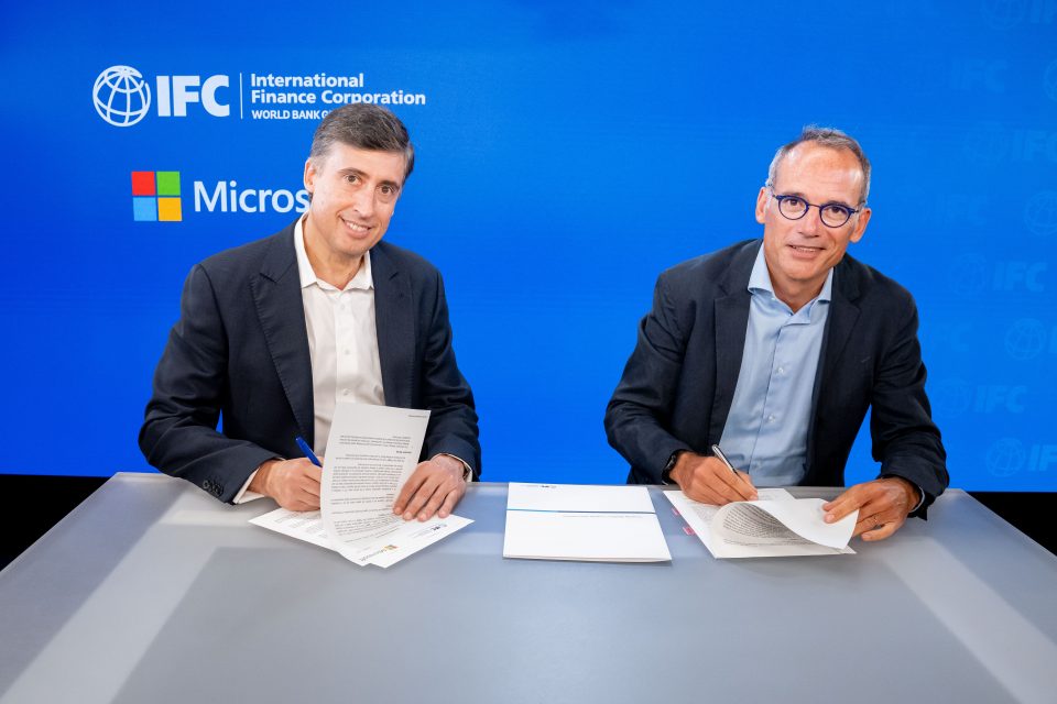 Dos personas sentadas frente a un escritorio firmando documentos