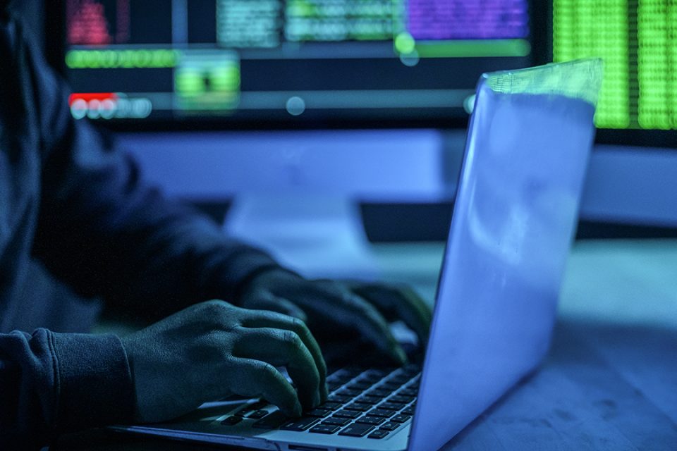 Acercamiento a una persona trabajando en una laptop en una sala llena de tableros