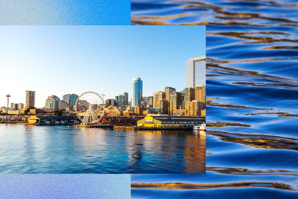 La imagen de la ciudad de Seattle con un paseo marítimo. Las características prominentes incluyen una rueda de la fortuna, varios edificios altos y el reflejo del horizonte en el agua. El fondo incluye una superposición de agua ondulante.