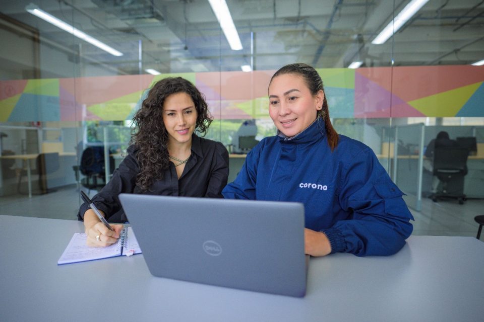 Dos personas en una planta de manufactura observan una laptop