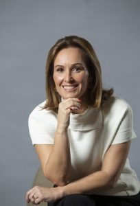 Una mujer con la mano en la barbilla sonríe para la cámara