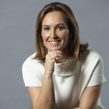 Una mujer con la mano en la barbilla sonríe para la cámara