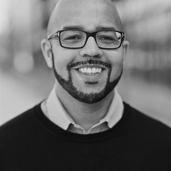 Close up of a man wearing glasses, a shirt, and a black sweater