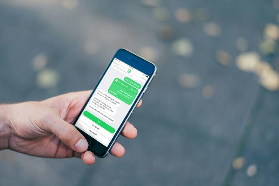 Mão masculina segura celular com o aplicativo Olivia na tela.