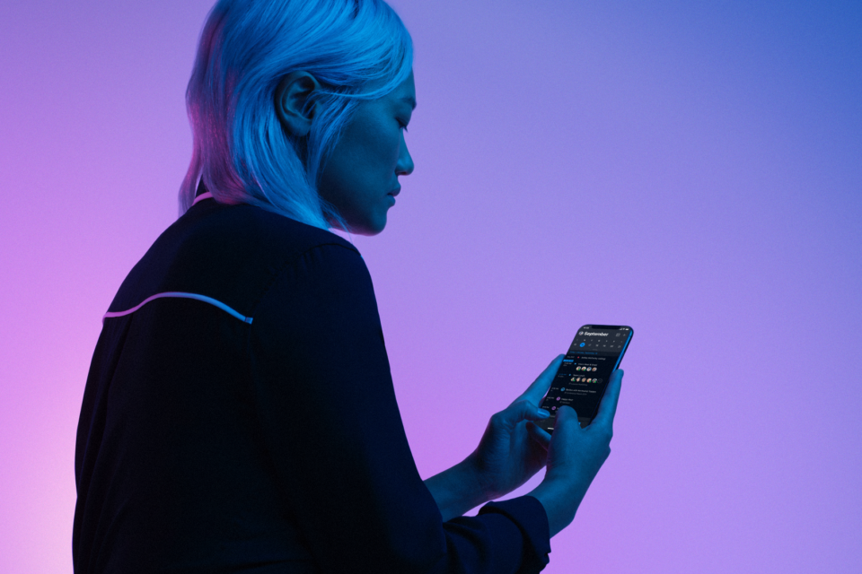 Mulher usa dispositivo móvel no modo escuro.