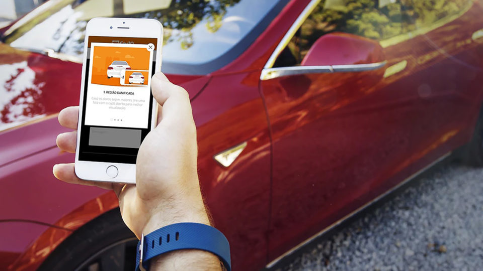 Homem segura celular com o app Car10 na tela.
