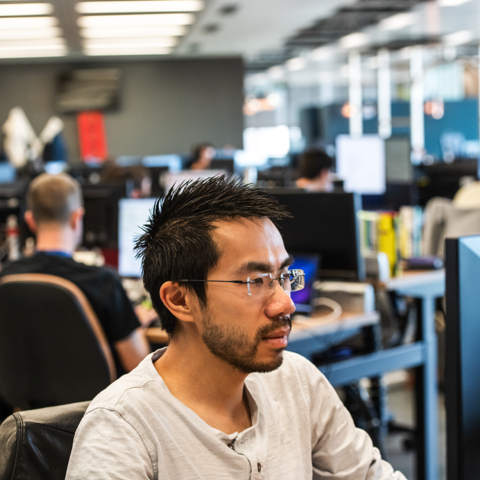 Homem de óculos trabalhando no computador em um escritório