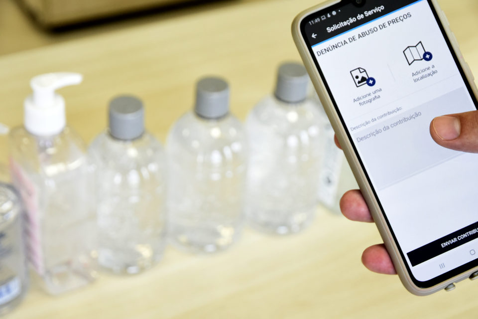 Celular com o app e alcool gel no fundo
