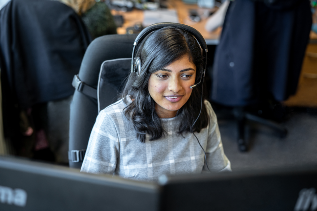 Mulher atrás de um computador com headphone