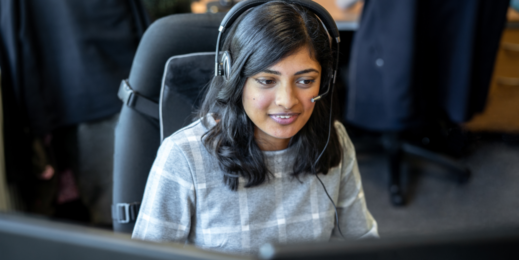 Mulher atrás de um computador com headphone