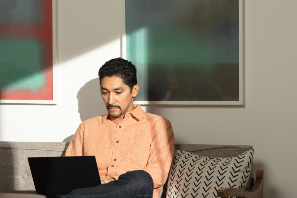 homem sentado no sofe com notebook no colo