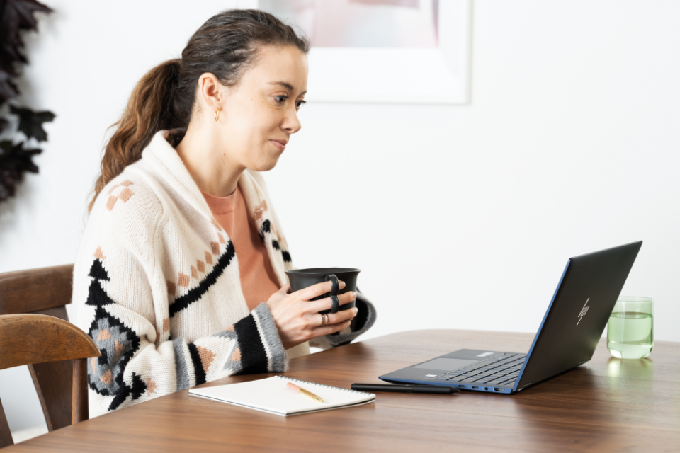 mulher segurando caneca olhando para computador
