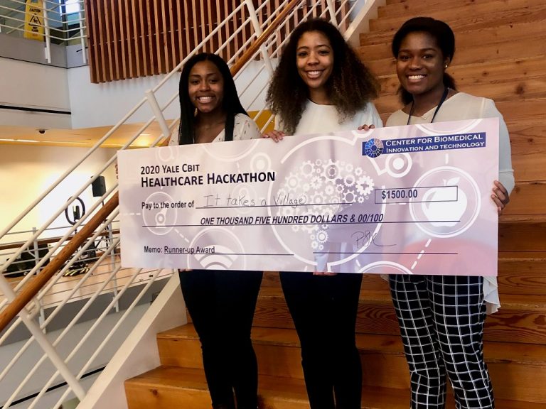 três mulheres segurando um cheque grande