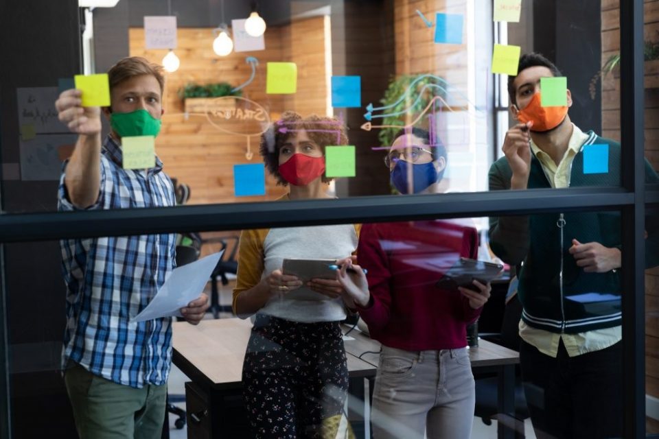 pessoas escrevendo e colando post its